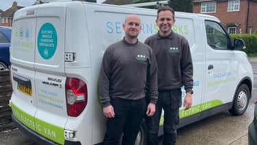 two men standing next to a van with a van in the background