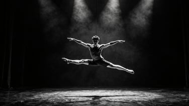 Wide stage shot from below, a dancer mid-air in contemporary suspension, arms extended, harsh stage lighting from above casting deep shadows, black floor, high-contrast monochrome atmosphere