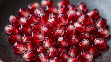 Macro photography of fresh, vibrant pomegranate seeds resting on a matte dark ceramic plate, capturing a sophisticated and moody culinary aesthetic.