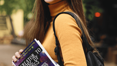 Young teen  girl with long brown hair, carrying the book Creator To King of Kings. She is smiling.