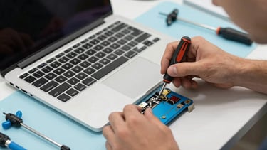 A professional technical workspace in Portugal with a high-end laptop being repaired. A technician's hands are visible using a precision screwdriver. The desk is organized with light grey tools and sky blue accents. The lighting is clean and natural, reflecting a reliable and modern service environment.
