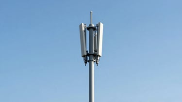 A minimalist shot of a modern UK telecommunications tower against a clear blue sky, bright neutral daylight, sharp focus