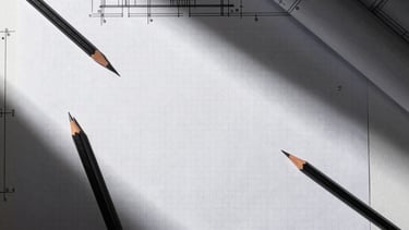 Top-down flat lay of a minimalist architectural workspace, technical drawing tools, sharp graphite pencils, and clean grid paper under high-contrast dramatic side-lighting.