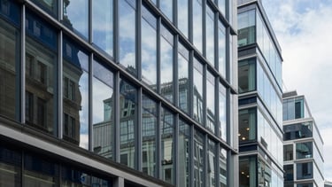 A professional and sophisticated photography shot of a high-end corporate office in London, United Kingdom. The scene features clean glass surfaces, steel blue accents, and a soft navy blue color palette. Modern architecture with natural light reflecting off polished surfaces, conveying a sense of integrity and financial excellence.