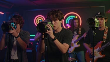 Lo-fi music video still, indie rock band performing with retro cameras, colorful neon overlays, playful and dynamic