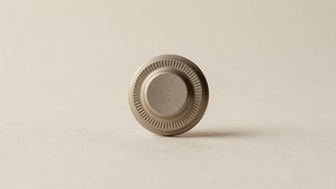 Macro studio shot of a textured 1kg coffee bag valve, soft diffused side light, neutral off-white background, minimalist aesthetic