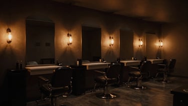 Wide environmental shot of a minimalist, dark-toned barber salon at dusk, warm incandescent lamps casting soft amber pools, empty and serene, 35mm photography