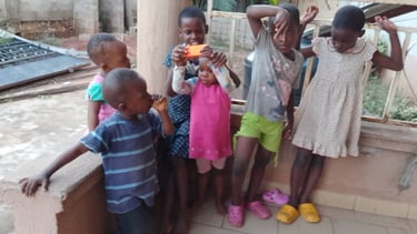 A group of six young African children playing together and posing on a porch.