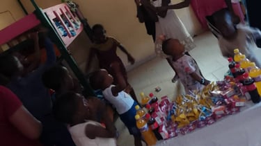 Children celebrating at a community event with snacks and juice bottles on a table in a room.