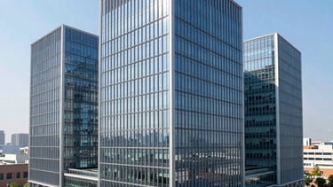 A high-angle architectural photograph of a modern glass-and-steel innovation center in a North American tech district. The setting is bright and professional, with a clear blue sky reflecting in the windows. The composition uses clean lines and perspective to convey reliability and growth, featuring a color palette of slate blue and light silver.