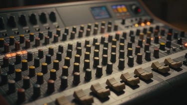 Cinematic close-up of an analog mixing console, warm practical lights, soft haze