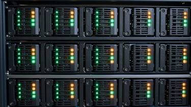 Neat rows of server hard drives with flashing green and amber LED indicators in a dark rack, crisp technical photography, 50mm