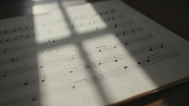 Close-up of handwritten musical notation on aged manuscript paper, soft natural window light, deep shadows, shallow depth of field.