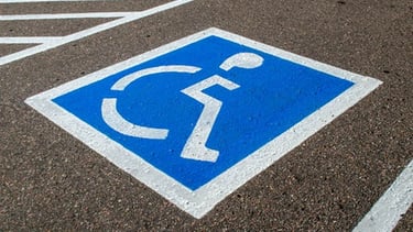 Blue and white handicap parking symbol painted on asphalt in a reserved accessible space.