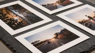 A collection of high-end photography prints laid out on a dark slate table. Modern, clean presentation in an art gallery setting.