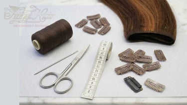 A brown hair extension kit with scissors, measuring tape, thread, and replacement clips on a table.