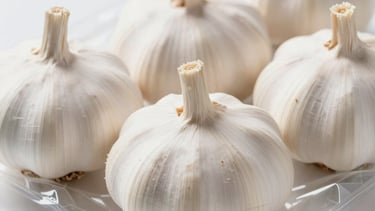 Fresh whole white garlic bulbs in a clear plastic grocery store tray package.