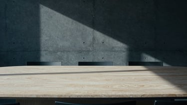 Architectural detail of a minimalist concrete and limestone boardroom, sharp geometric shadows, cool overcast daylight, desaturated navy tones, 35mm
