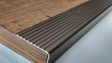 foto zoom de uma cantoneira de aluminio sobre piso de madeira