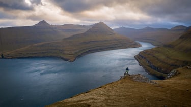 View over Funningur fjord with low clouds, steep mountains and layered depth, classic Faroe Islands scenery