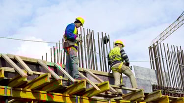 Tra team constructing a reinforced concrete building with scaffolding and structural beams on-sit