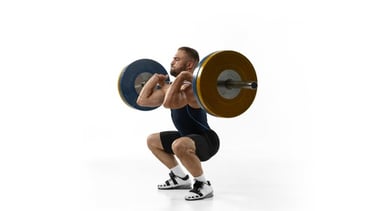 A muscular man performing a front squat with a heavy barbell on a white background.