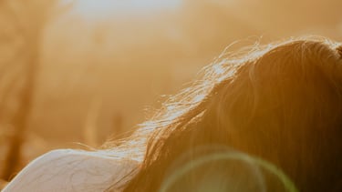 woman lying in nature with soft sunshine eliciting feelings of emotional balance