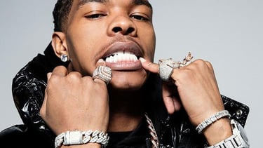 Rapper Lil Baby wearing diamond grillz, heavy gold chains, and luxury jewelry.