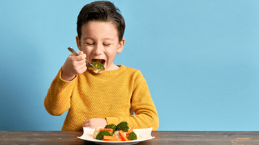 enfant qui mange ses légumes avec le sourire