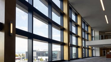 Wide architectural shot of a modern corporate office interior in Salt Lake City, crisp morning window light, deep navy and gold accents, structured lines, 35mm.