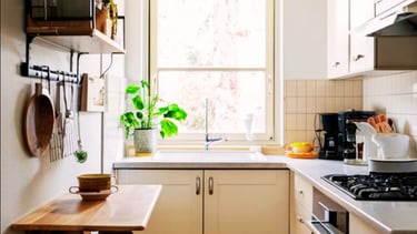 Small kitchen interior with white cabinets, patterned floor tile, and a folding wooden breakfast bar.