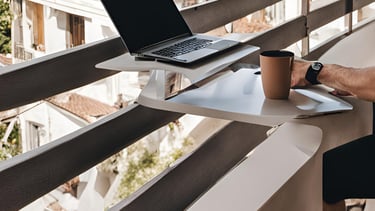 a man sitting at a balcony with a laptop computer