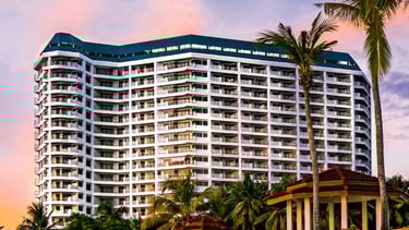a large white building with a gazeboar and palm trees