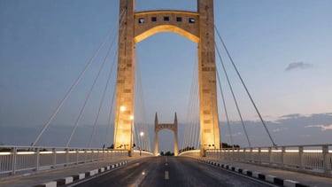 A dynamic evening shot of a bridge project, with integrated sand-colored stone and modern LED lighting reflecting off the asphalt. The composition is clean and symmetrical, emphasizing reliability.