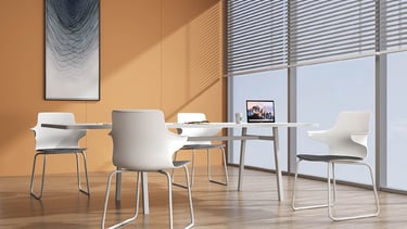 White Dora chairs around a table in a sunlit conference room with orange wall