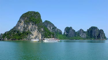 White cruise boats sailing past the iconic limestone karst mountains in Ha Long Bay, Vietnam.