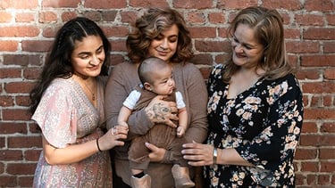 Imagen de tres mujeres sosteniendo a un bebé,