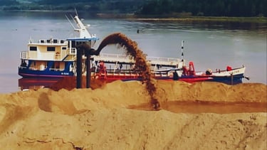 a boat is being loaded with sand and a crane