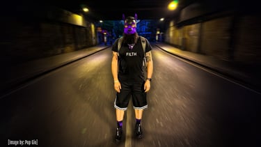 Man in pup mask standing in the middle of a deserted street at night.