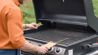 A man sitting on the sidewalk engaged in repairing tools, surrounded by various items and a bicycle with a covered load. The setup suggests a makeshift workstation with a collection of tools and materials scattered around.