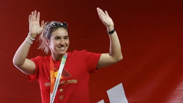a woman in a red shirt and sunglasses is holding a medal