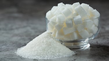 Granos de azúcar en un bowl, con azúcar desparramada