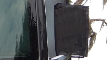Close-up of a black mesh cover protecting a side mirror on a large motorhome or RV.