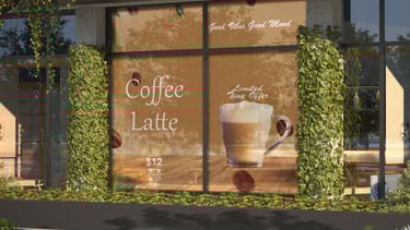 The image shows a café storefront window decorated with a coffee advertisement. The background is wa