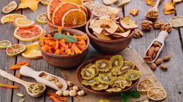 Bowls con trozos de frutas deshidratadas: kiwi, limón, mango, pomelo, naranja. Algunos frutos secos.