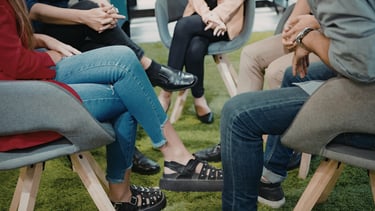 Diverse professional group sitting in a circle for a team building workshop or support group meeting.