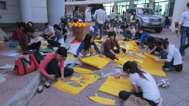 a group of people sitting on the ground with yellow paper