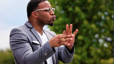 a man in a suit and sunglasses is holding a cell phone