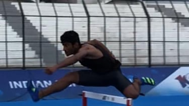 a man is jumping over a hurdle in a stadium