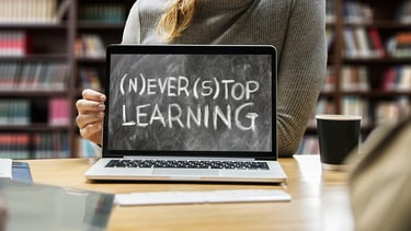 a woman showing a laptop computer screen saying never stop learning